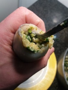 Prendete quindi il calamaro, stringetelo dalla punta della testa per far uscire eventualmente l'aria e, con l'aiuto di un cucchiaino, imbottite il calamaro. Spingete ogni cucchiaino di imbottitura più a fondo che potete (se ne avete uno con il manico lungo sarebbe perfetto) in modo che il calamaro risulti alla fine gonfio e turgido.