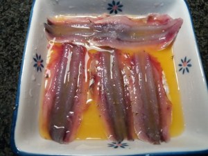 Alici marinate all'arancia su scarole con olive nere capperi pinoli e uva passa