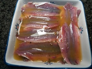 Alici marinate all'arancia su scarole con olive nere capperi pinoli e uva passa