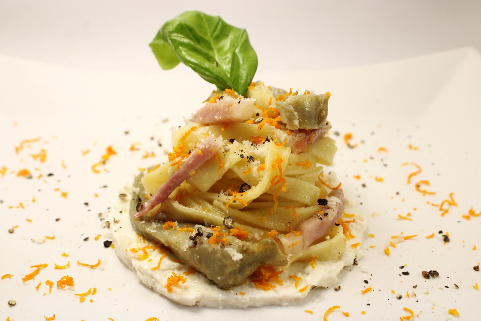 Tagliatelle profumate all'arancia con carciofi e speck su ricotta di bufala