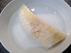 Stoccafisso glassato allo zafferano su vellutata di patate e piselli con terra di olive nere